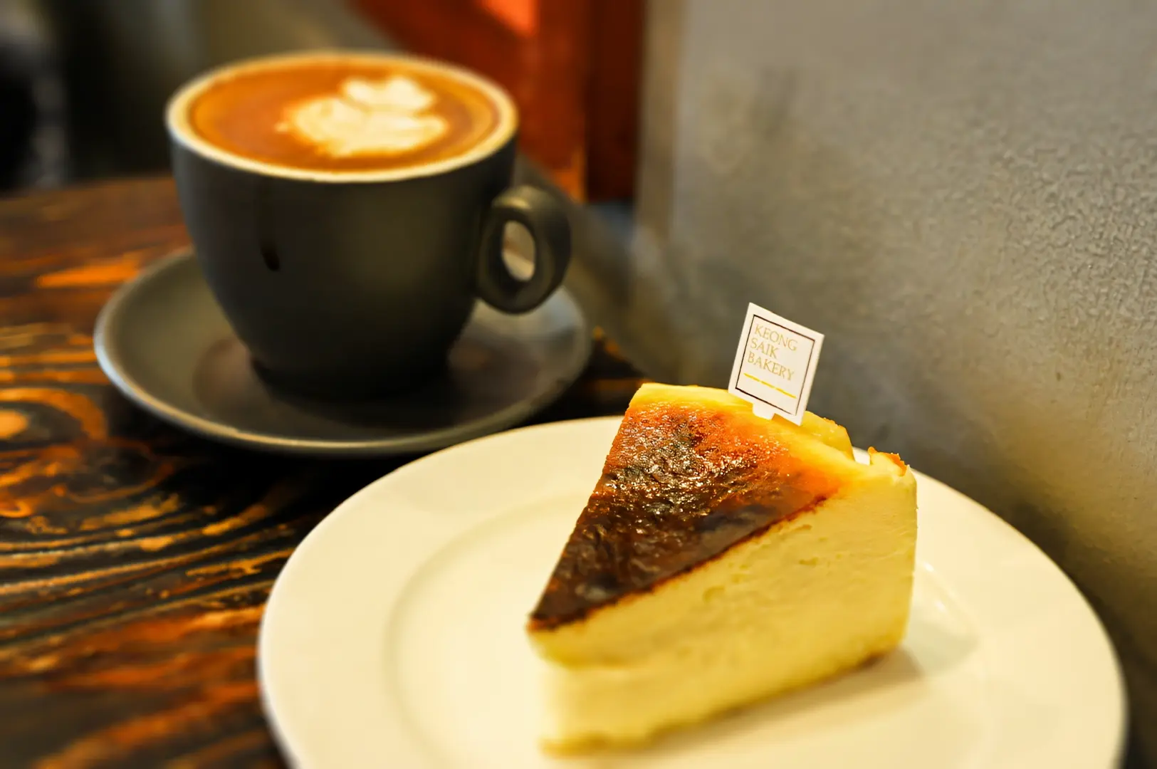 Side‑angle café shot of a slice of burnt cheesecake and a cup of coffee in Singapore, a smart budget brunch choice pairing pastry and coffee without paying weekend tax