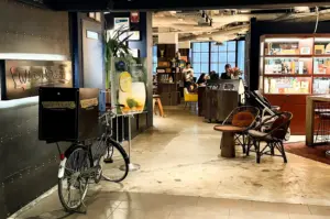 Wide-angle eye-level shot of Wild Honey cafe interior Singapore, stylish brunch space with industrial decor, seating area, bicycle display and cozy Orchard Road dining atmosphere