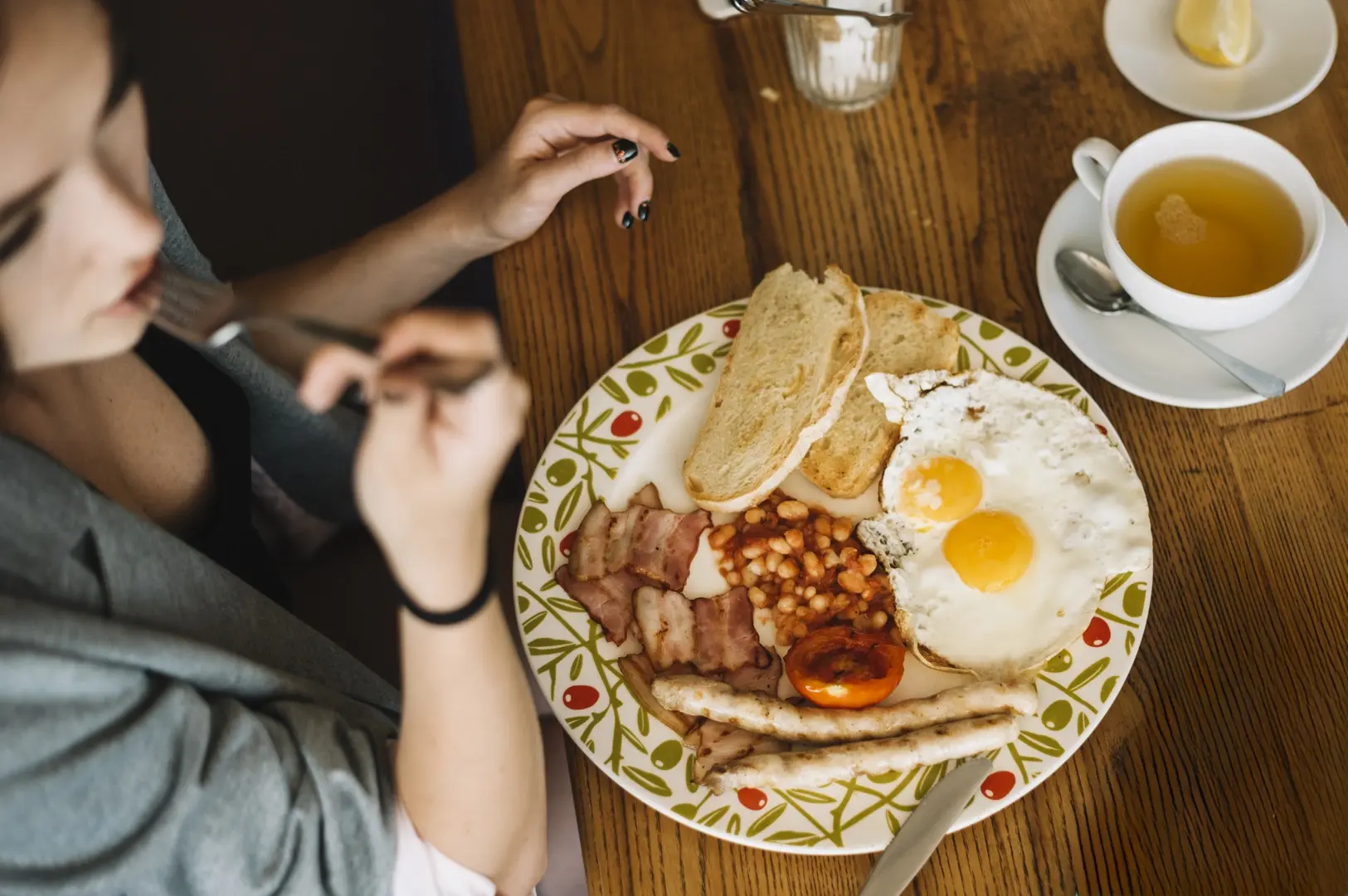 High‑angle shot of a classic big breakfast in Singapore with eggs, bacon, beans, sausages, toast, and tea, illustrating common weekend brunch choices that often cost more