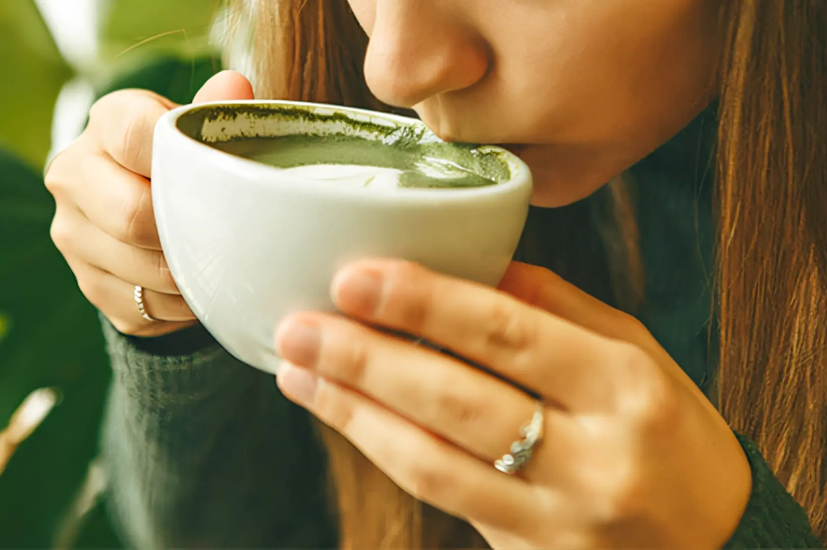 Close-up side angle of a person sipping a creamy matcha latte from a ceramic cup, highlighting smooth texture and beginner-friendly matcha drinks at a cafe