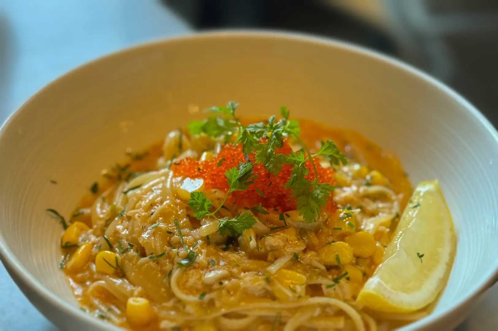 Close‑up shallow‑depth shot of a creamy seafood pasta topped with herbs and fish roe, a value‑for‑money brunch dish in Singapore that justifies café pricing