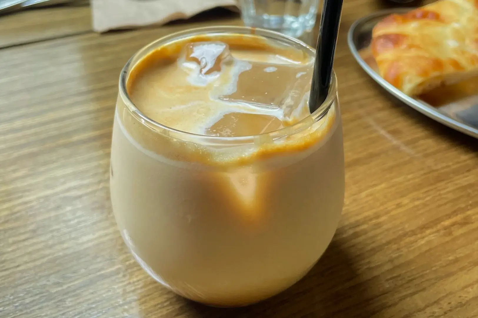 Close‑up side‑angle shot of an iced latte served in a glass at a Singapore café, a popular brunch beverage that often adds hidden costs to weekend brunch bills