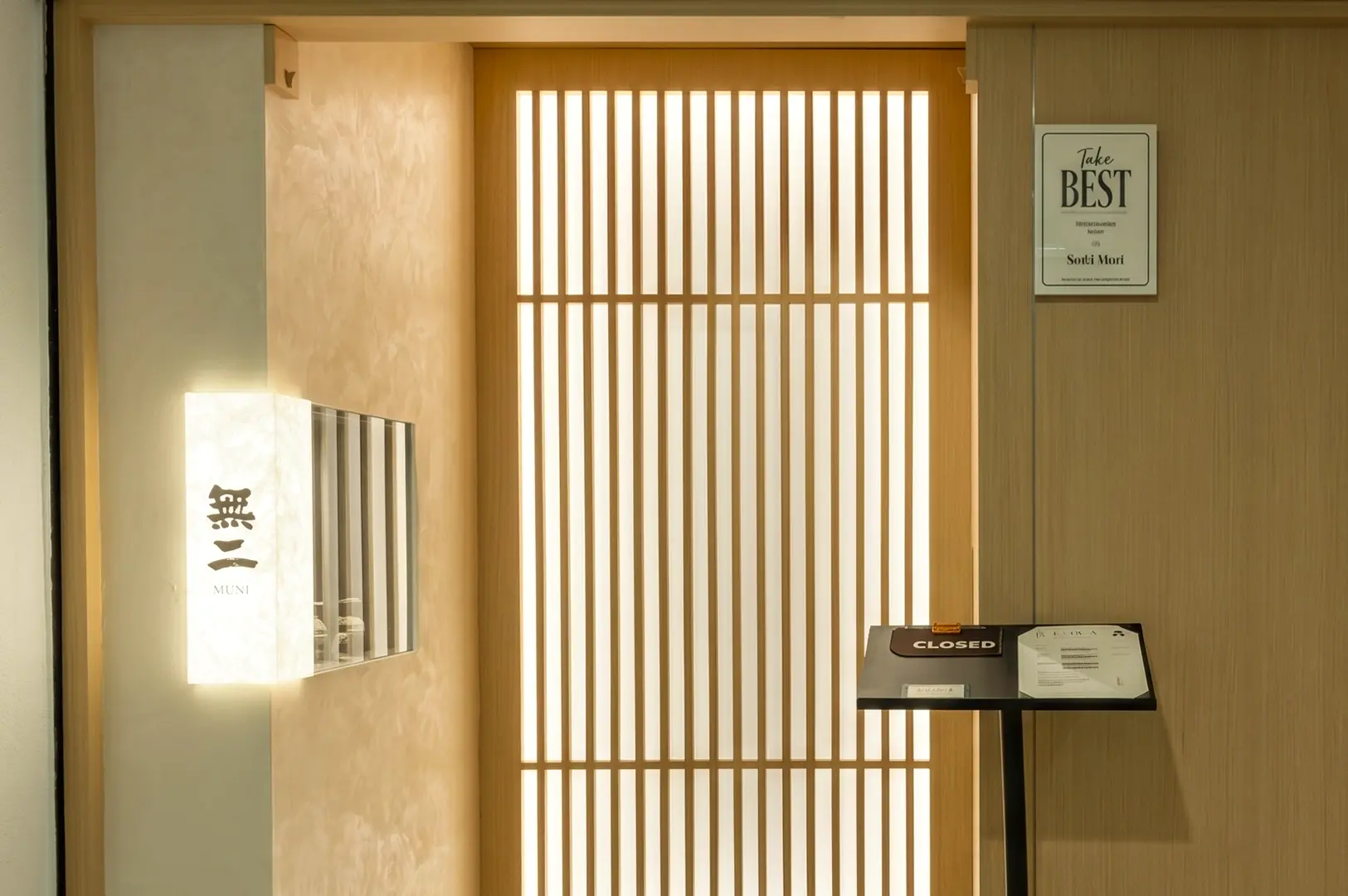 Front-facing wide shot of Sushi Muni Singapore entrance with shoji-style sliding doors, minimalist Japanese restaurant design and omakase dining ambiance