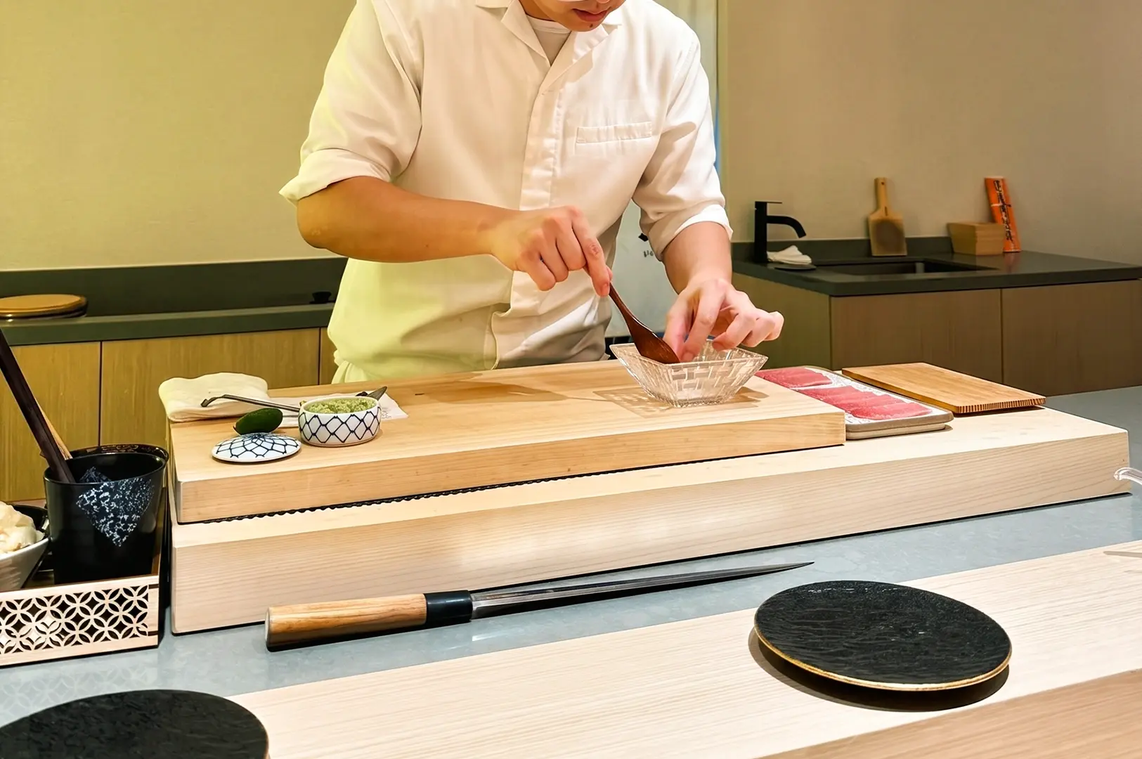 Sushi chef preparing ingredients at omakase counter in Sushi Muni Singapore, close-up eye-level shot highlighting Japanese fine dining craftsmanship