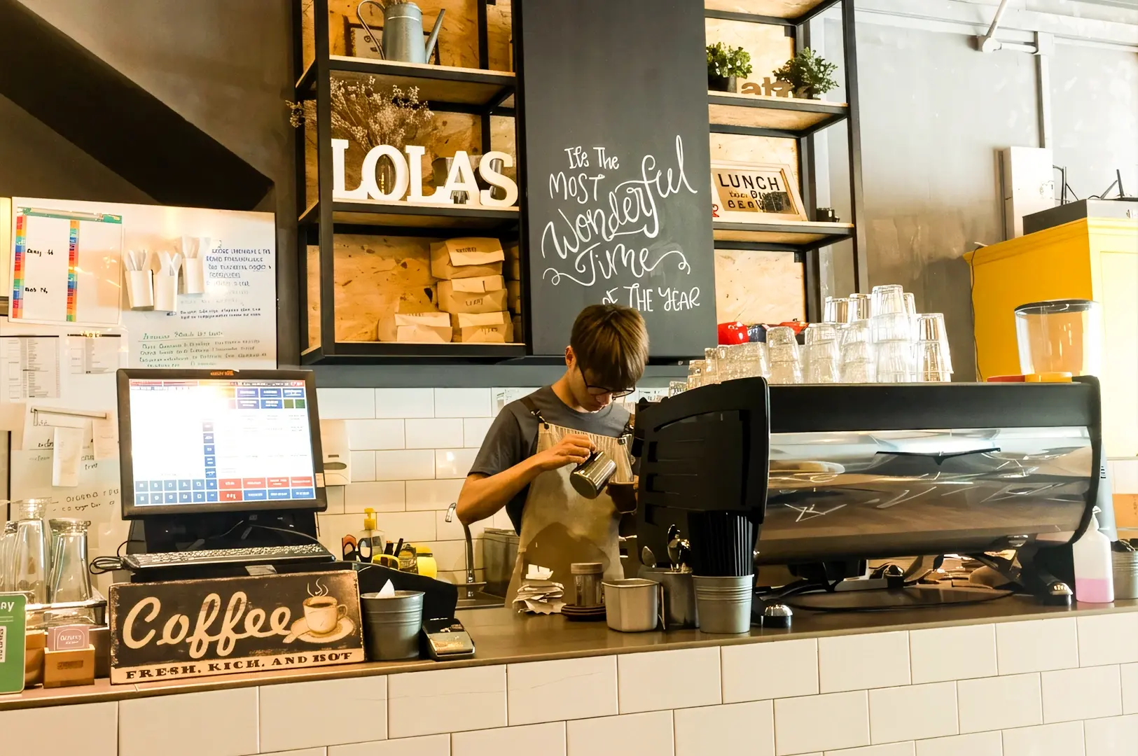 Eye-level medium shot of barista preparing freshly ground coffee behind the counter at Lola’s Cafe Kovan, featuring Scandinavian-style interior, espresso machine, and brunch cafe ambience in Singapore