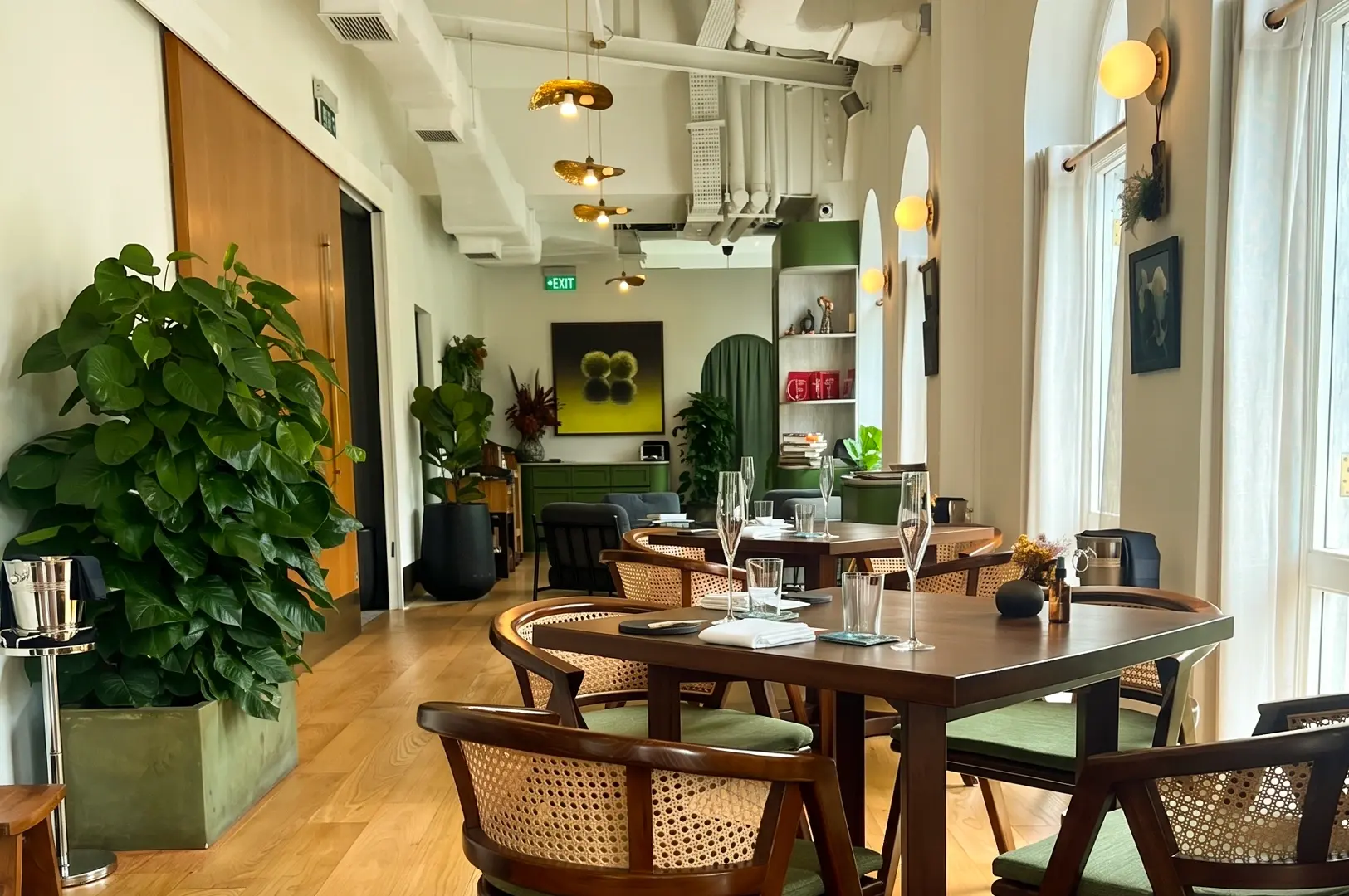 Eye-level wide-angle shot of Restaurant JAG Singapore dining room at Robertson Quay, featuring modern elegant interiors, wooden tables, rattan chairs, plants, and natural light highlighting a Michelin-starred fine dining ambience