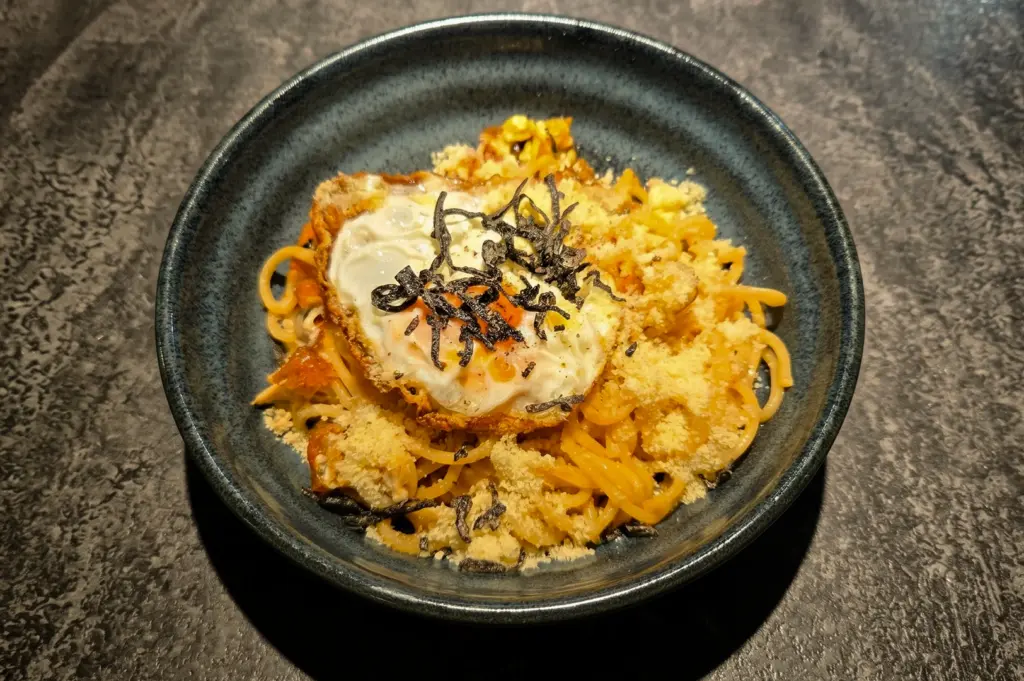 Top-down view of Sio Pasta Singapore's signature Fried Egg, Cheese and Salted Kelp Pasta, featuring handmade Japanese-style noodles, crispy fried egg, umami-rich kelp, and grated cheese at Raffles City.