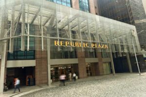 Street-level view of the Republic Plaza building entrance in Singapore featuring gold lettering under a glass canopy.